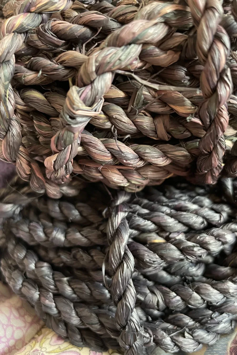 Close view of thick braided fibre coils in muted pink, green and grey