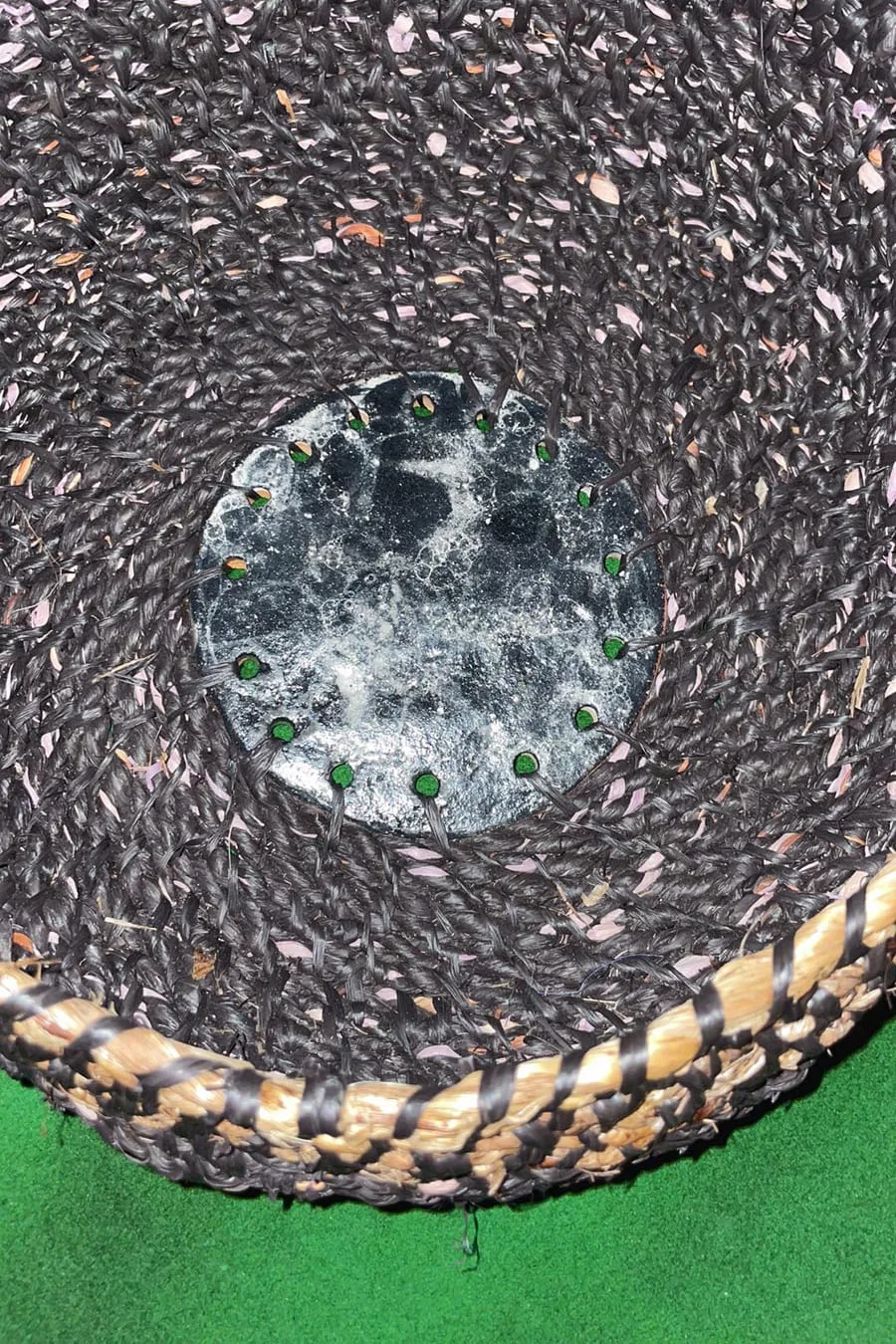 Looking into a dark coiled vessel with a round glazed clay centre and a striped rim