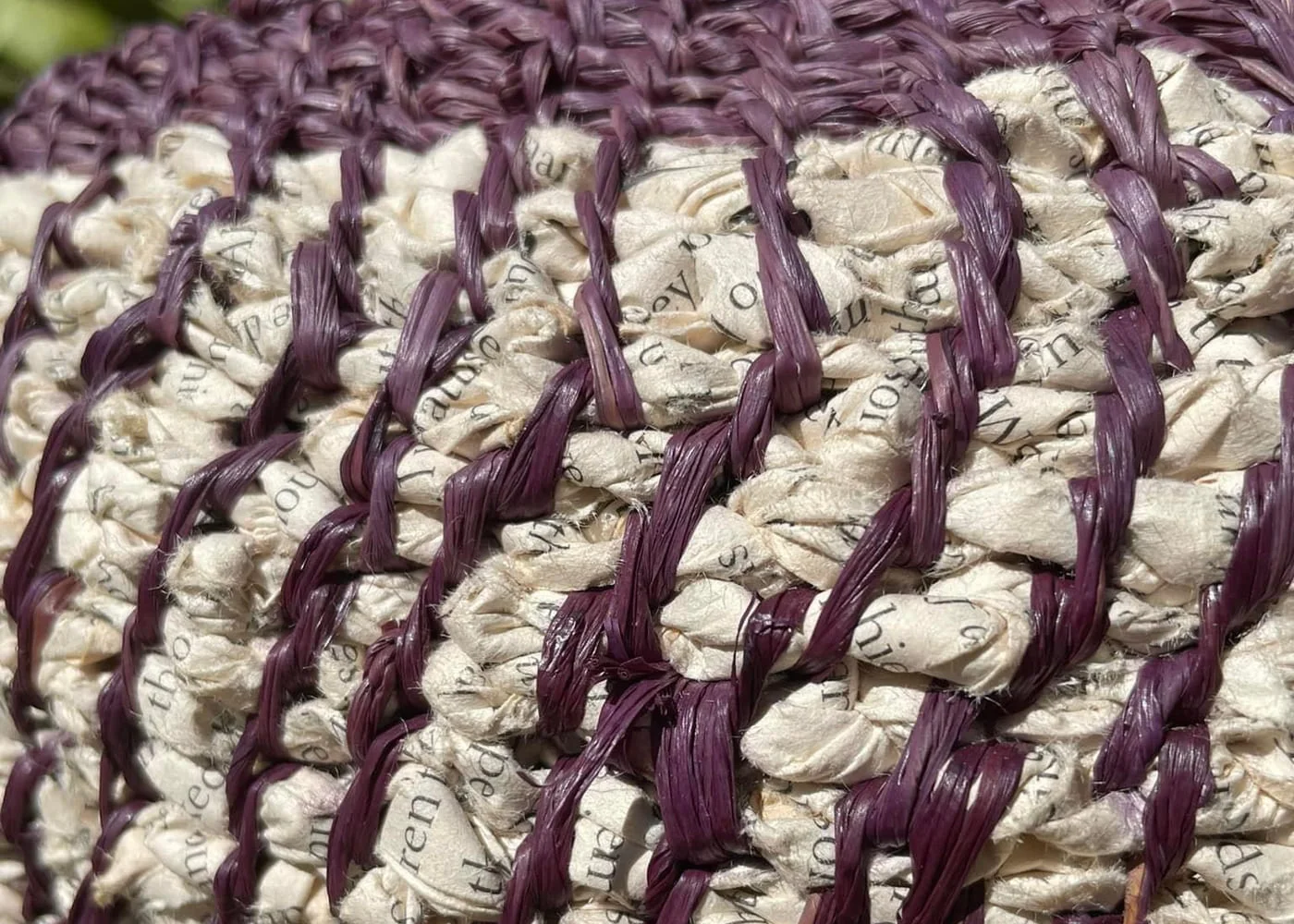 Close view of cream printed-paper coils bound with plum stitching