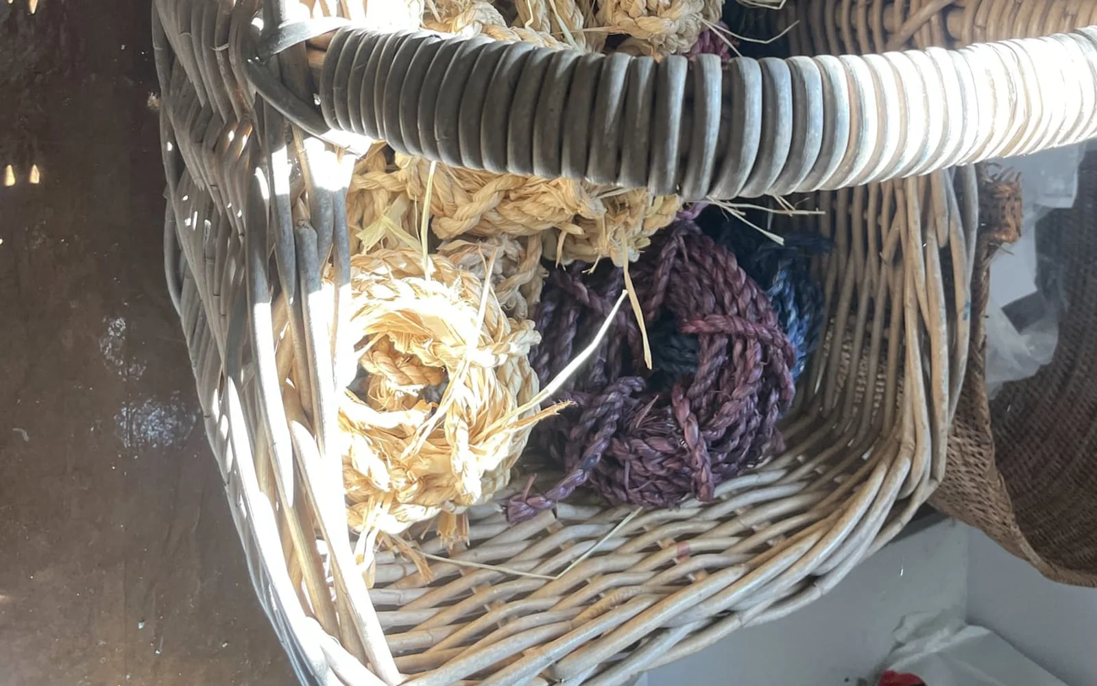 A cane basket holding bundles of dried fibre and dyed yarn