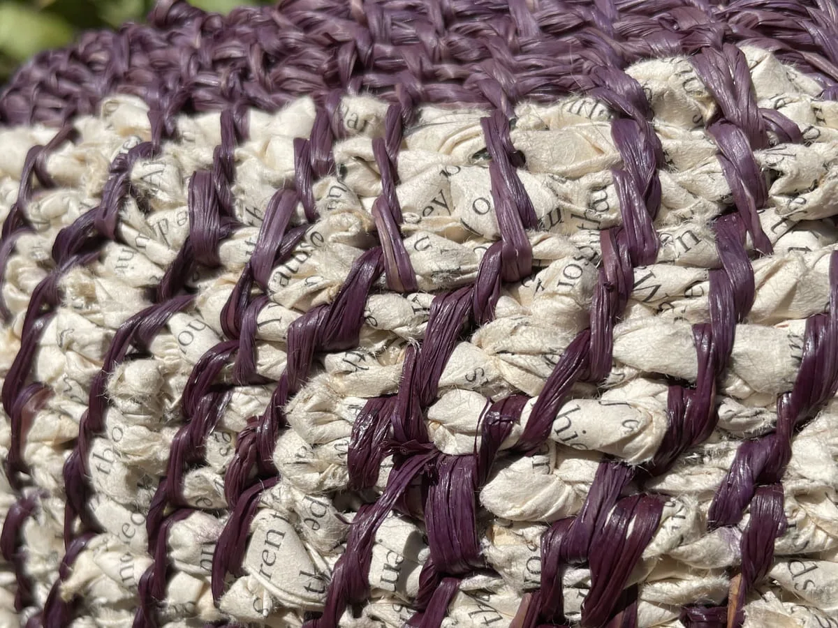 Close view of cream printed-paper coils bound with plum stitching
