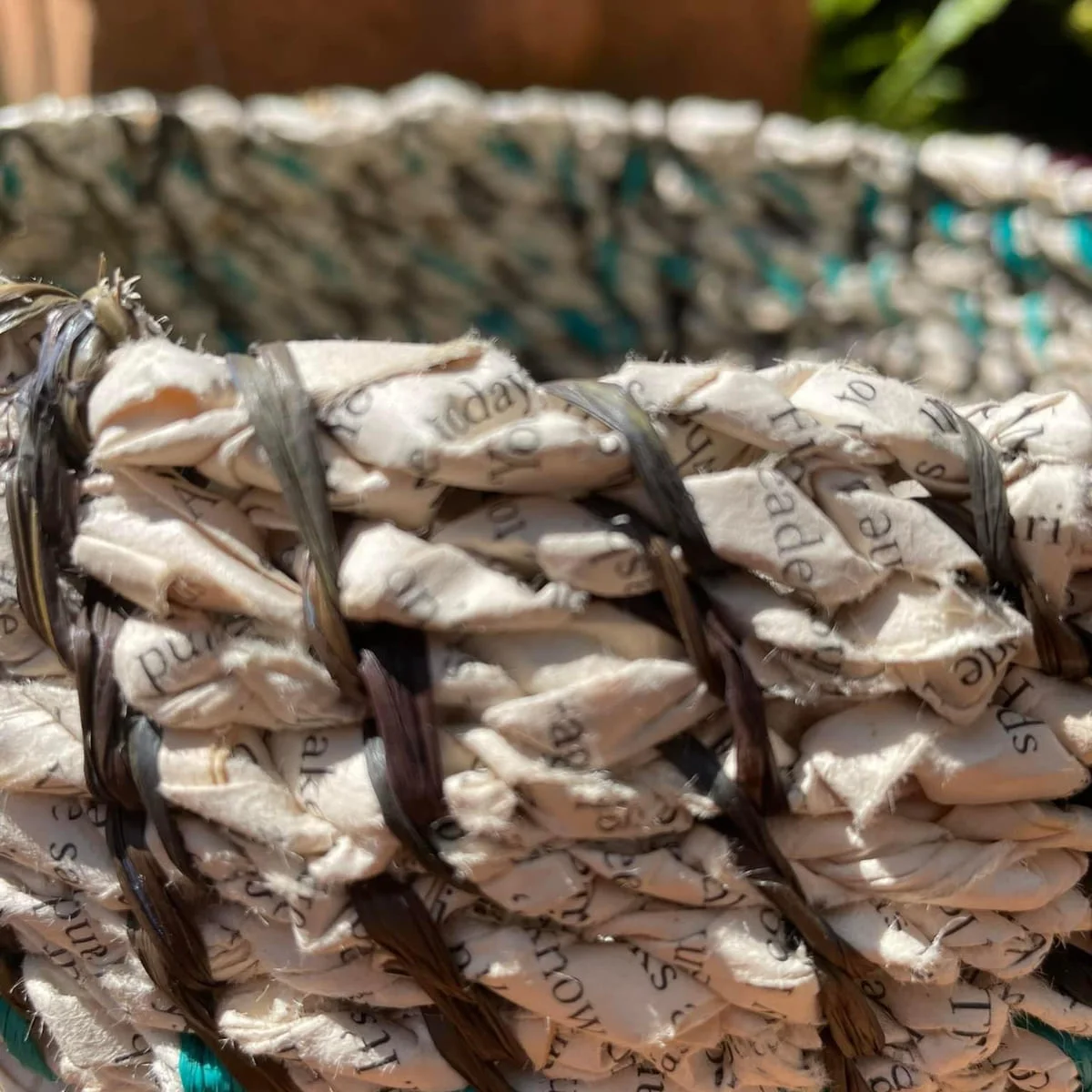 Close view of a basket rim of folded printed paper bound with dark fibre