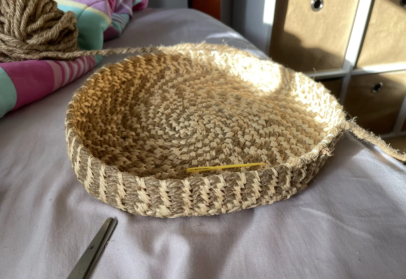 A coiled tray in progress, with natural fibre still attached