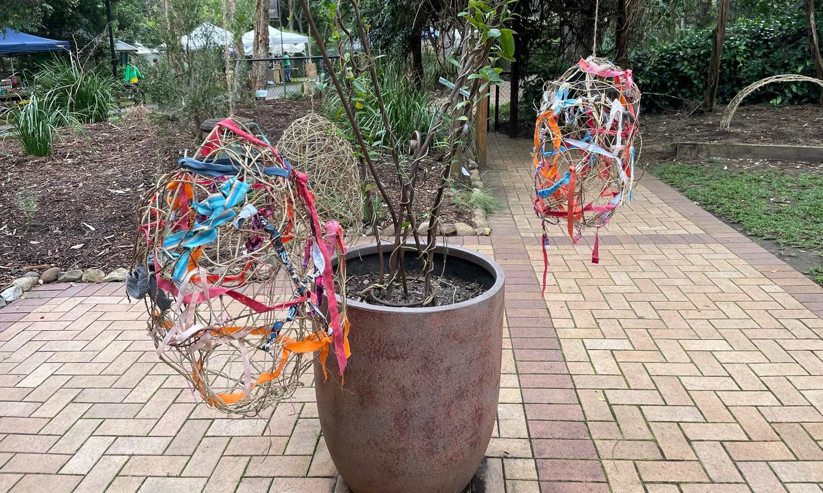 Woven fibre spheres hung along a paved garden path